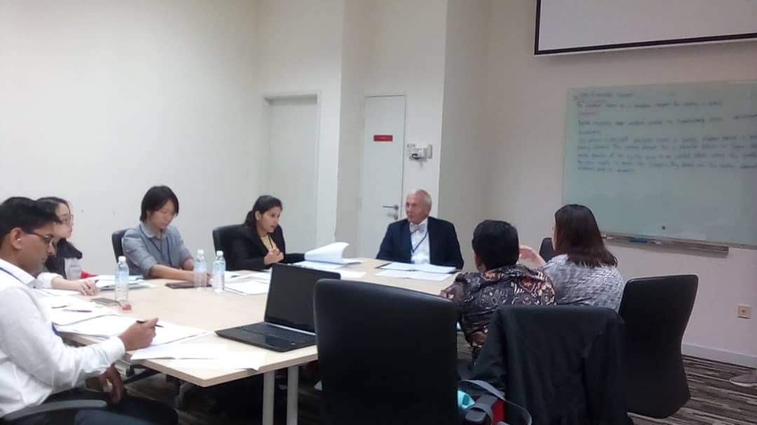 Small group of patent professionals seated around a table during a claim drafting tutorial.